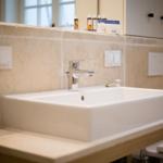 Sink on wooden vanity with stone wall and faucet
