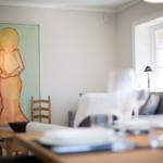Dining room with table, chairs, and wall art. Window with lamp.