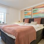 Schlafzimmer mit Bett, zwei Nachttischen und Wandbildern.
