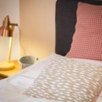 Bettkopf mit Kissen, Nachttisch mit Lampe und Schale