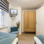 Zwei Betten, Kleiderschrank, TV und Fenster mit Jalousie.