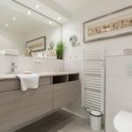 Moderne Badezimmer mit Waschtisch, Spiegel und Toilette.