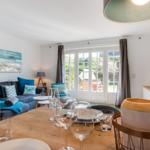 Wohn- und Essbereich mit Sofa, Tisch und Fenster zum Garten.