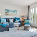 Wohnzimmer mit Sofa, Sitzhocker und französischen Fenstern.
