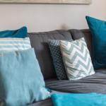 Ein grauer Sofa mit blauen und gestreiften Kissen.