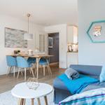 Wohn- und Essbereich mit blauen Stühlen und Sofa. Wanddekoration mit Seehund und Anker.