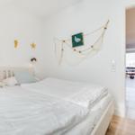 Bedroom with bed, wall decor, and view into the kitchen.