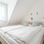 Bedroom with sloped ceiling, bed, window, and wall decor.