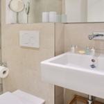 Bathroom with shower, sink, and toilet. Soap and rubber duck on the sink.