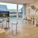 Living and dining area with TV, table, chairs, and staircase.