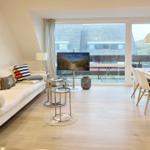 Living room with sofa, TV, and dining area. View of terrace and roof.