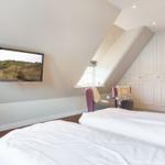 Schlafzimmer mit Dachschrägen, TV und Kleiderschrank.