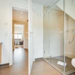 Badezimmer mit Dusche, Toilette und Waschbecken. Durchgang zur Wohnfläche.