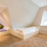 Dachgeschosszimmer mit drei Betten und zwei Fenstern.