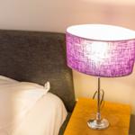 Bettkopfteil mit Nachttisch und Lampe mit lila Schirm