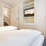 Schlafzimmer mit Bett, Kleiderschrank und TV in Wandnische