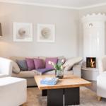 Wohnzimmer mit Sofa, Sesseln, Kamin und Tisch mit Blumen.