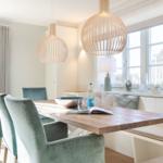 Esszimmer mit Holztisch, Sitzbank und zwei hängenden Lampen.
