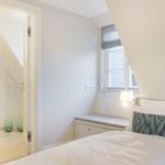 Schlafzimmer mit Bett, Fenster und Blick in Badezimmer