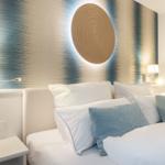 Schlafzimmer mit Bett, Kissen und Wanddekoration.