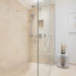 Dusche mit Glaswand, Steinwand und Pflanze im Bad.