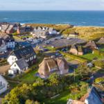Dorf mit Strand, Häusern und grünen Wiesen an der Küste