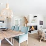 Essbereich mit Holztisch und Stühlen, Kamin und Sitzgelegenheiten im Wohnbereich.