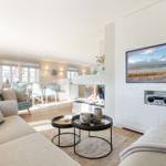 Wohnzimmer mit Kamin, Sofa und Fernseher an weißer Wand.