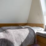 Schlafzimmer mit Dachschrägen, Bett, Fenster und Nachttisch.