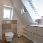 Badezimmer mit Dachschrägen, Waschbecken und Toilette unter Fenster