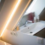 Waschbecken mit Spiegel und roter Dekoration unter Dachschrägen