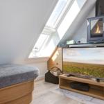 Dachgeschosszimmer mit TV, Kamin und Dachfenstern.