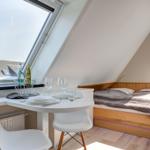 Schlafzimmer mit Dachfenster, Esstisch und Bett unter Dachschräge.