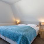 Bedroom with sloped ceiling, bed with blue quilt, and two nightstands.