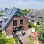 Modern villa with terrace, garden, and grill area. Wooden deck with loungers and table.