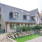 House with stone wall, green lawn, and dark roof