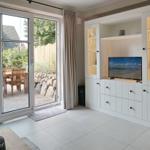 Living room with TV, wine cabinet, and terrace access