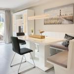 Dining area with white table, bench, and wall art featuring a lighthouse.