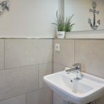 Sink with mirror, plant, and anchor decoration on the wall.