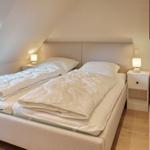 Bedroom with double bed, nightstands, and lamps under sloped ceiling.