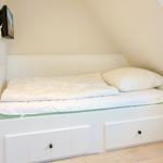 Bedroom with bed, TV, and storage space under the bed.
