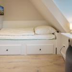 Bedroom with double bed, nightstand, and TV mounted on the wall.