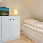 Bedroom with double bed, TV, and bedside lamp.