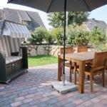 Patio with wooden table, chairs, and umbrella. A beach chair is on the left.