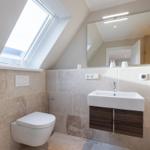 Bathroom with sloped ceiling, sink and toilet under roof