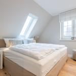 Bedroom with skylight, window and bed with white bedding.
