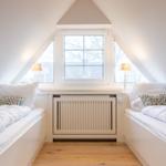 Two beds under a skylight with wooden floor and radiator.