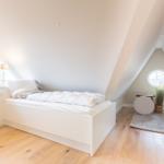 Bedroom with sloped ceiling, window, and bed on pedestal.