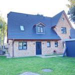 House with brick facade, dark blue roof, and garden with seating area.