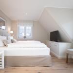 Bedroom with sloped ceiling, bed, TV, and chair.